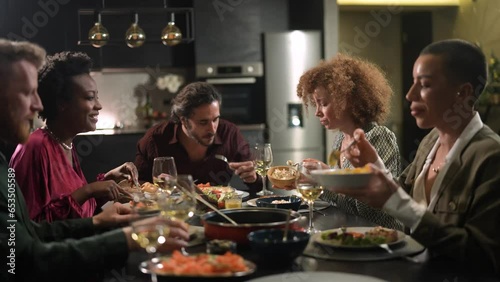 Diverse age group of friends having lunch and wine together in the kitchen at home