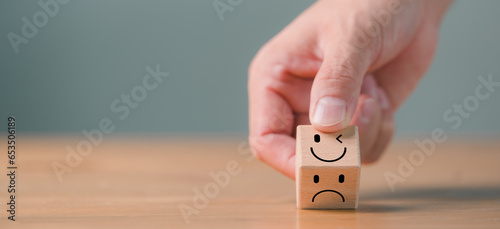 Mental health and emotional state concept, Smile face in bright side and sad face in dark side on wooden block cube for positive mindset selection. photo