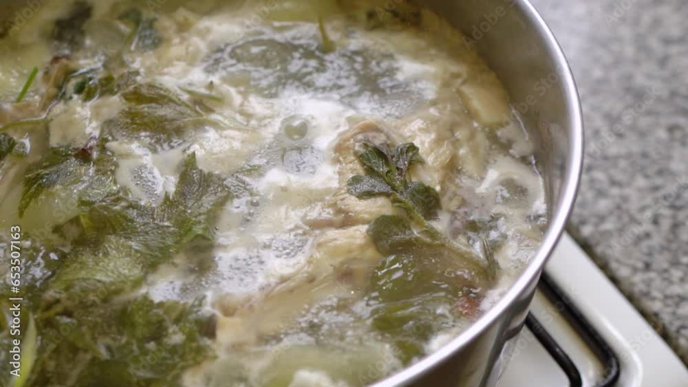 Soup simmering on the stove. Herbs and chicken cooking together. Handheld Soup simmering on the stove. Herbs and chicken cooking together. Handheld