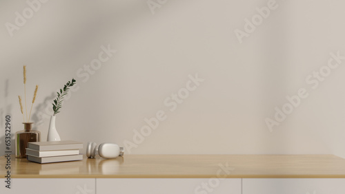 Empty space on a wood tabletop against the white wall with books, headphones, and vases on the table