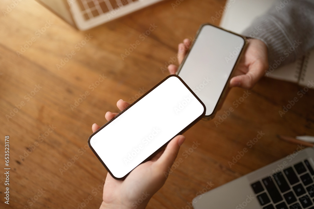 Close-up image of a woman is sharing files or a contact on her smartphone to her friend's smartphone Close-up image of a woman is sharing files or a contact on her smartphone to her friend's smartphone
