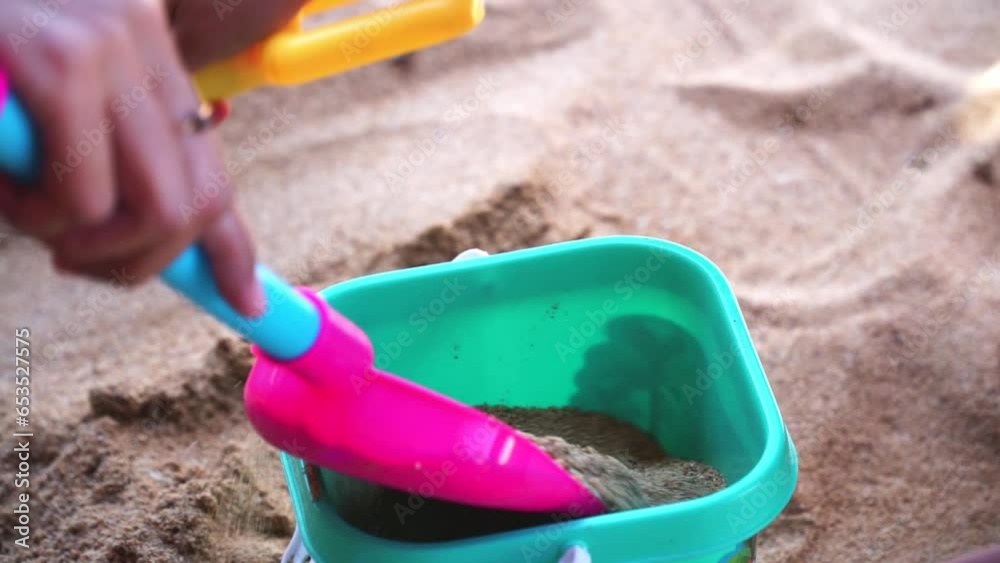 Closeup shot hands of child playing beach sand with shovel and bucket Closeup shot hands of child playing beach sand with shovel and bucket