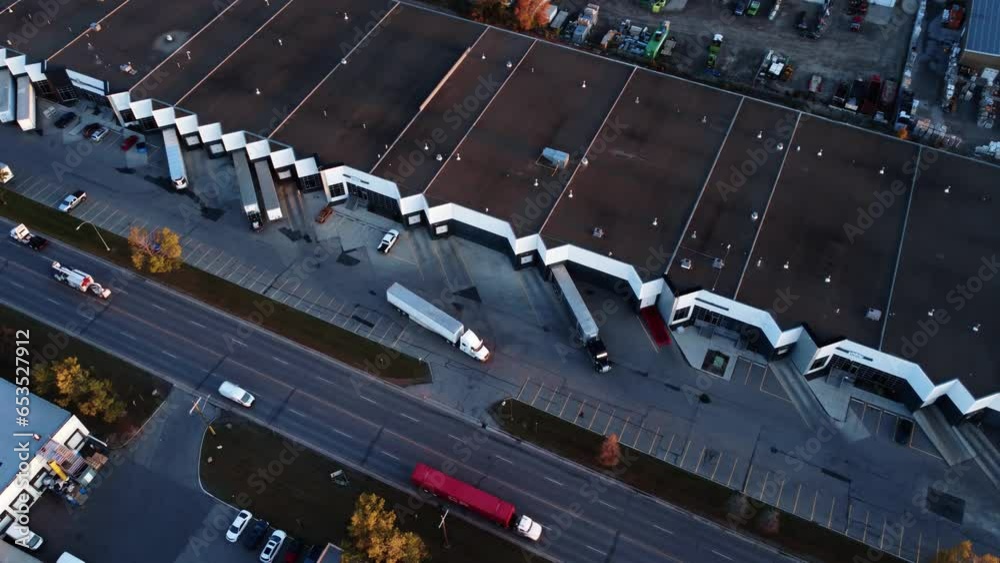 Semi-truck backing up towards warehouse loading dock. Drone view.