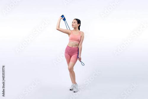 Fototapeta Naklejka Na Ścianę i Meble -  Young energetic asian woman in sportswear with jumping or skipping robe posing portrait in studio shot on isolated background. Cardio exercise tool and healthy body care lifestyle. Vigorous