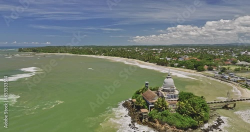 Matara Sri Lanka Aerial v1 cinematic drone fly around Parewi Duwa Temple on a rocky island capturing long stretch sandy beach and Kotuwegoda village town views - Shot with Mavic 3 Cine - April 2023 photo