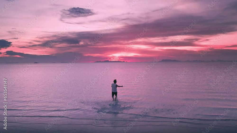 Escape to Freedom. Man traveler Running Towards the Sea enjoying Beautiful Purple Sunset. Freedom and Adventure, Man Jogging to Ocean during Stunning Sunset. Escape to Freedom concept, cinematic shot. Escape to Freedom. Man traveler Running Towards the Sea enjoying Beautiful Purple Sunset. Freedom and Adventure, Man Jogging to Ocean during Stunning Sunset. Escape to Freedom concept, cinematic shot.