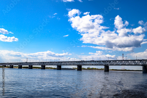 A motorway and railway bridge across the river. Blue calm river water and blue cloudy sky