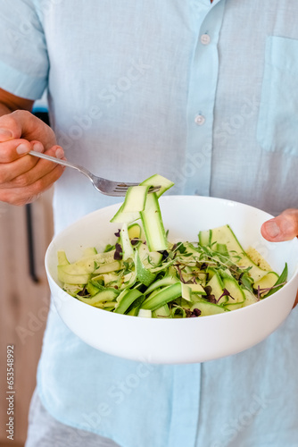 Man holding bowl alternative vegetable homemade zucchini pasta salad. Zoodle