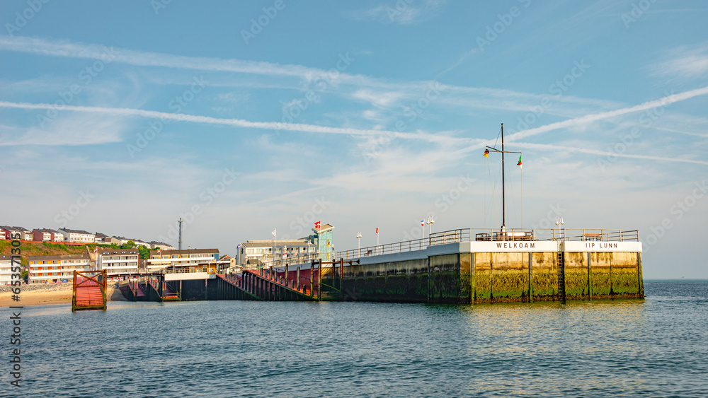 Helgoland, Germany - July 5, 2015: Pier at sunset. Cityscape of Helgoland, popular German paradise holiday island in the North Sea, summer, with many hotels, clean beach and rich marine wildlife.