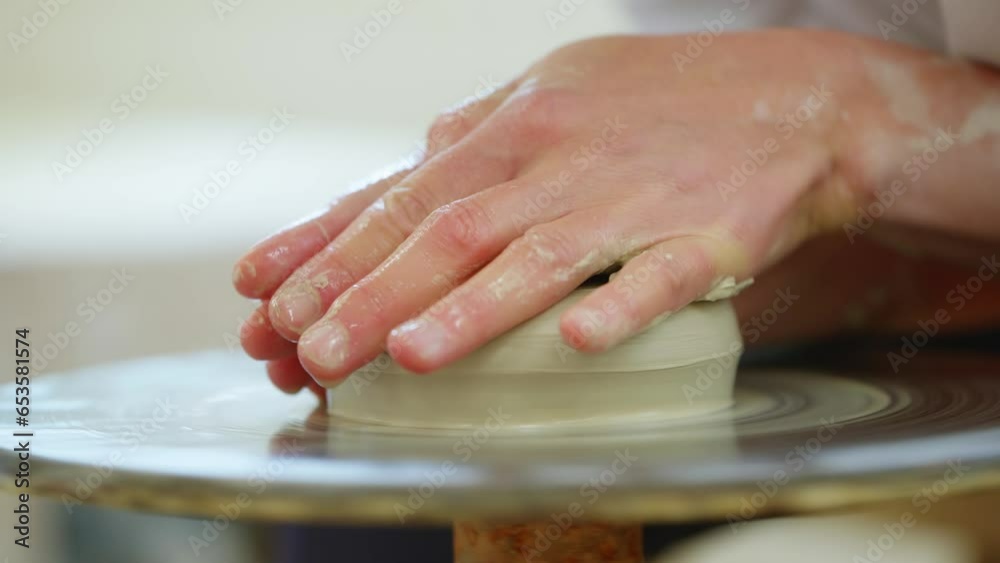 Hands shaping clay on a spinning potter's wheel
