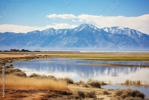 A view of Farmington Bay in 2016 from Antelope Island depicting the reflection of the Wasatch Mountain Front in water, with a coastline of salt and algae in Davis County, Utah. Generative AI
