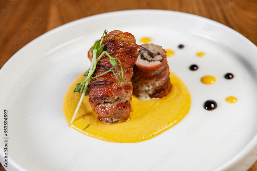 restaurant dish on a wooden table, chicken rolls in bacon restaurant dish on a wooden table, chicken rolls in bacon