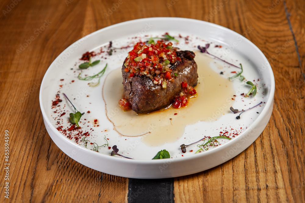 restaurant dish on a wooden table, steak, vegetables, sauce restaurant dish on a wooden table, steak, vegetables, sauce