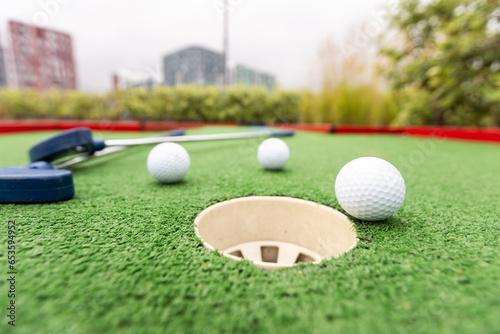 Golf stick and ball on green grass close up.