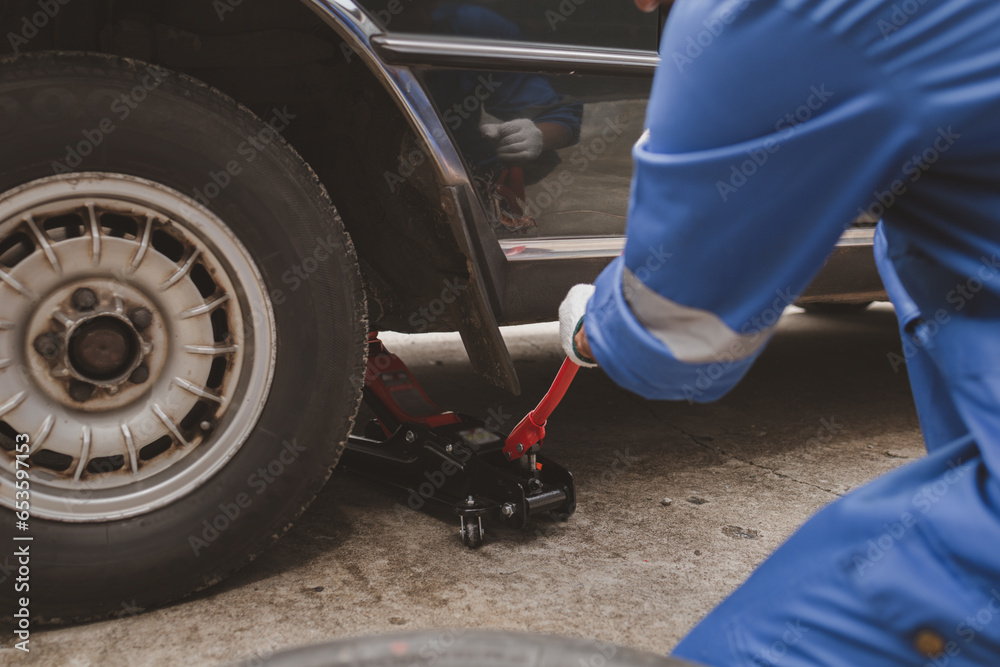 Car mechanic is inspecting tires and replacing worn tires through long hours of work, car repairs, car breakdowns, punctured tires. Concept of car tire maintenance and car repair. Car mechanic is inspecting tires and replacing worn tires through long hours of work, car repairs, car breakdowns, punctured tires. Concept of car tire maintenance and car repair.
