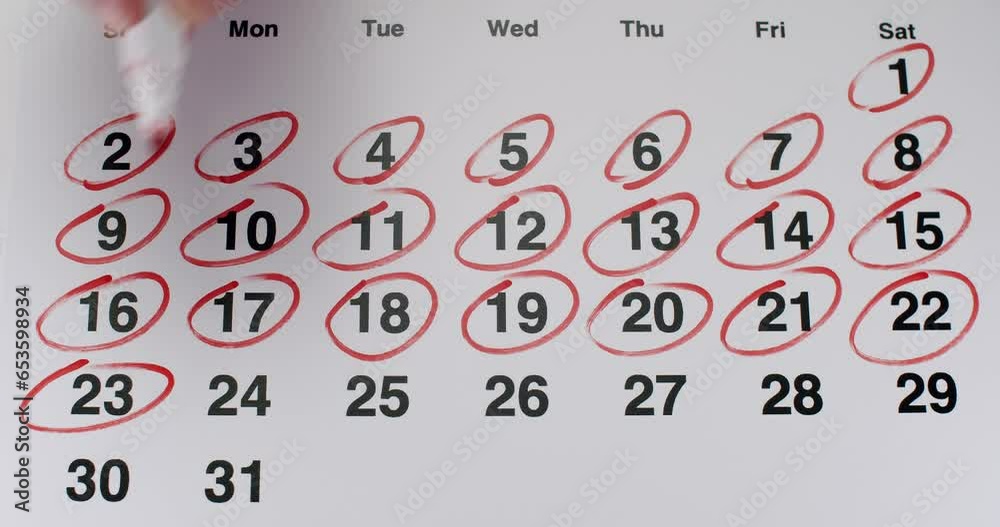 Person hand with red marker marking days at paper calendar and circle