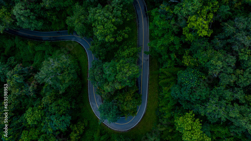 Aerial top view road in forest with car motion blur. Winding road through the forest. Car drive on the road between green forest. Ecosystem ecology healthy environment road trip. © Darunrat