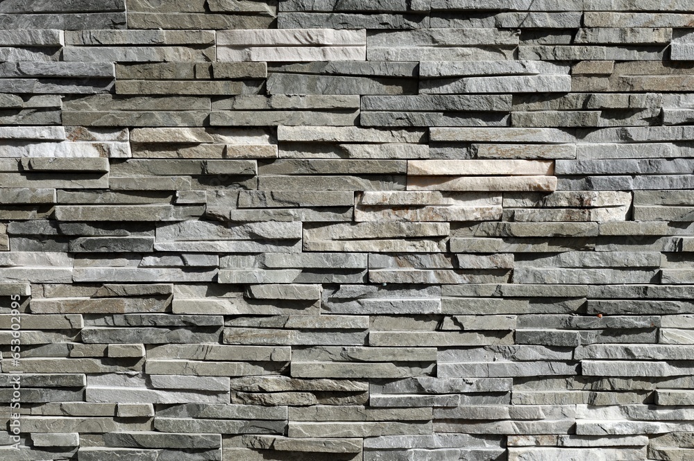 Fototapeta premium Stone cladding wall made of striped stacked slabs of natural gray and white rocks. Panels for exterior, background and texture. 