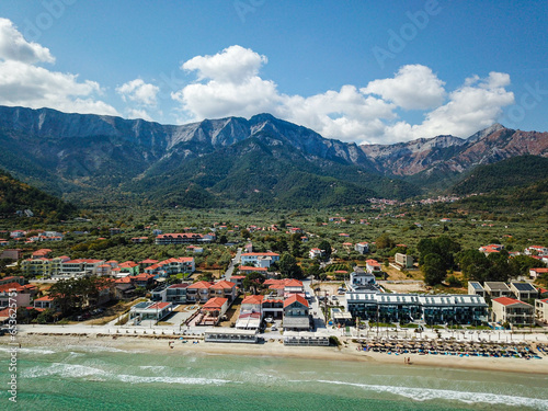 Aerial drone view from the Aegean sea of the shore of the Golden Beach area in Thassos Island , Greece , showing the resorts and hotels , tourist accommodation , the pure white sand shore