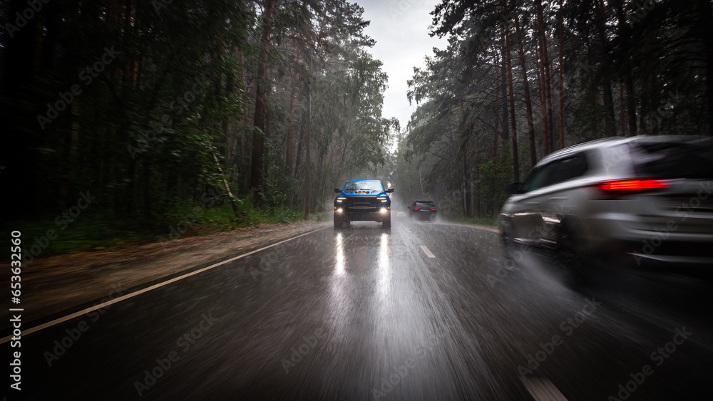 a blue new pickup truck is driving along a highway in the forest, with blurred cars - obrazy, fototapety, plakaty 