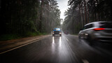 a blue new pickup truck is driving along a highway in the forest, with blurred cars