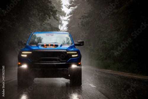 A blue new pickup truck is driving along a highway in the forest with a blurred background. Fast driving © Виталий Сова