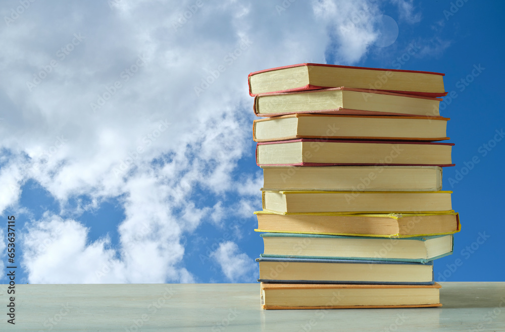 Stack of books with blue sky and clouds background, inspiration,imagination,fantasy,literature,reading, learning concept Stack of books with blue sky and clouds background, inspiration,imagination,fantasy,literature,reading, learning concept