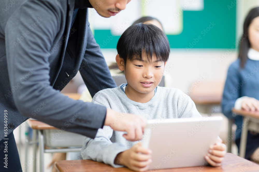 タブレットPCで勉強をする小学生と先生 タブレットPCで勉強をする小学生と先生