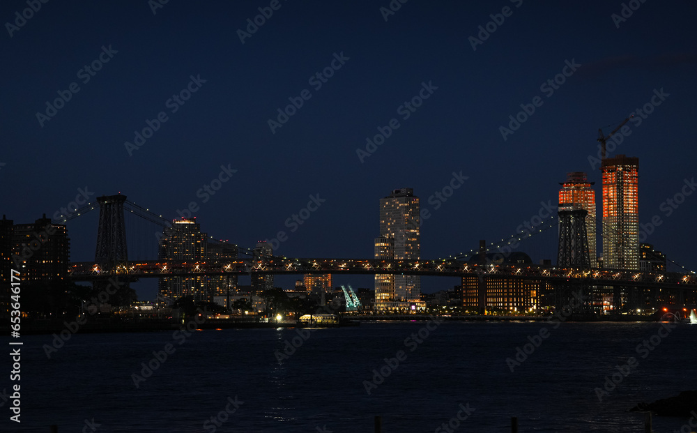 New York skyline by night. Landscape photo during the evening, view to Brooklyn and Manhattan bridge and landmark skyscraper office buildings from New York, America.