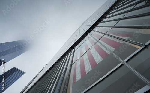 Wide angle photo with the national flag of America hanged on a skyscraper office building in downtown Manhattan. Concept image for America.