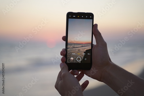 Hands holding phone take a photo beach night sunrise