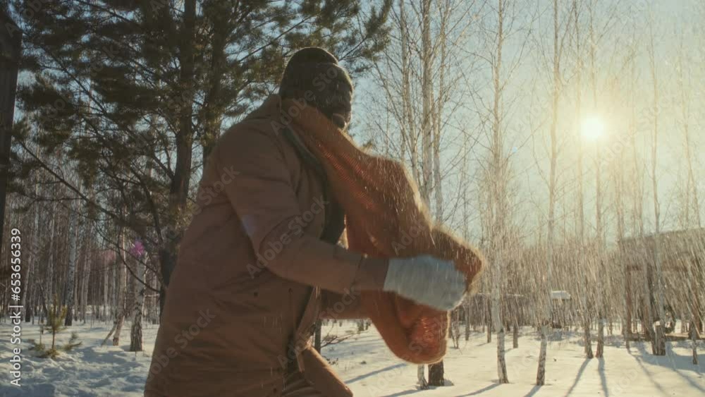 Cheerful African American man playing snowball fight with family or friends in local park on sunny winter day Cheerful African American man playing snowball fight with family or friends in local park on sunny winter day