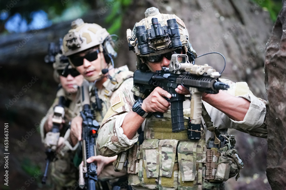 Military army soldiers tactical team, commando group moving cautiously in forest area, kneeling and looking around, covering comrades, controlling sectors. Commander showing halt or stop hand signal Military army soldiers tactical team, commando group moving cautiously in forest area, kneeling and looking around, covering comrades, controlling sectors. Commander showing halt or stop hand signal