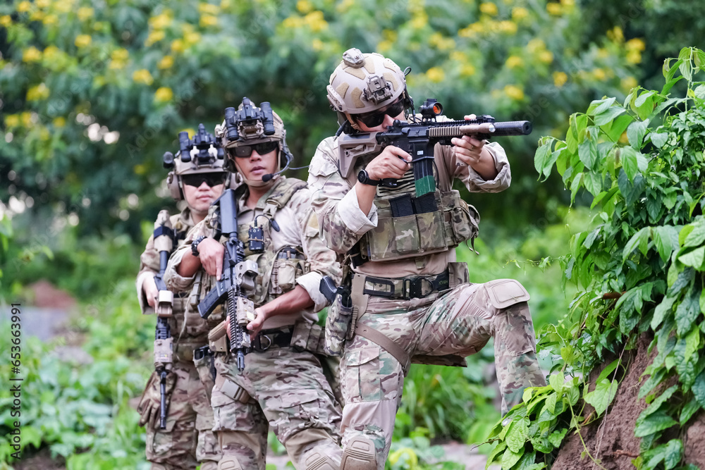 Military army soldiers tactical team, commando group moving cautiously in forest area, kneeling and looking around, covering comrades, controlling sectors. Commander showing halt or stop hand signal