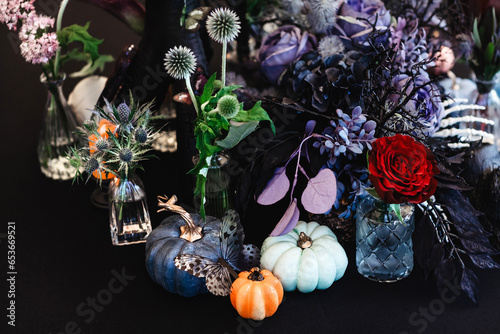 Autumn table composition with three colourful pumpkins and plants in dark purple tones. The theme of the holiday Halloween.