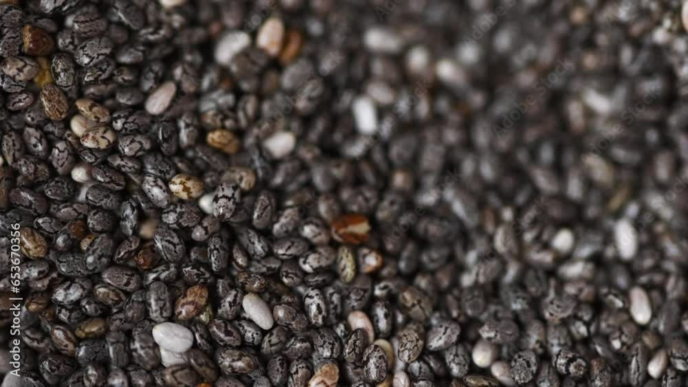 Pile of Chia Seeds are mixed with a shiny spoon. Top view and selective focus. Healthy diet. Agriculture and seed growing.