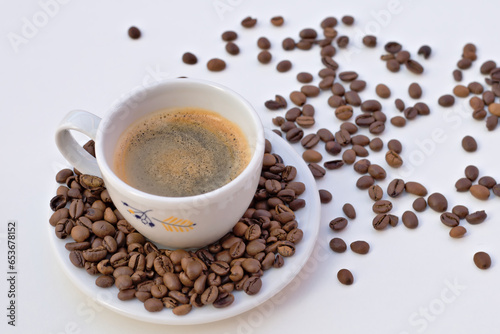 Cup of black coffee and saucer with coffee beans on white background.