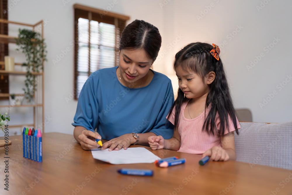 Happy family mother and daughter study or draw together at home in living room Happy family mother and daughter study or draw together at home in living room