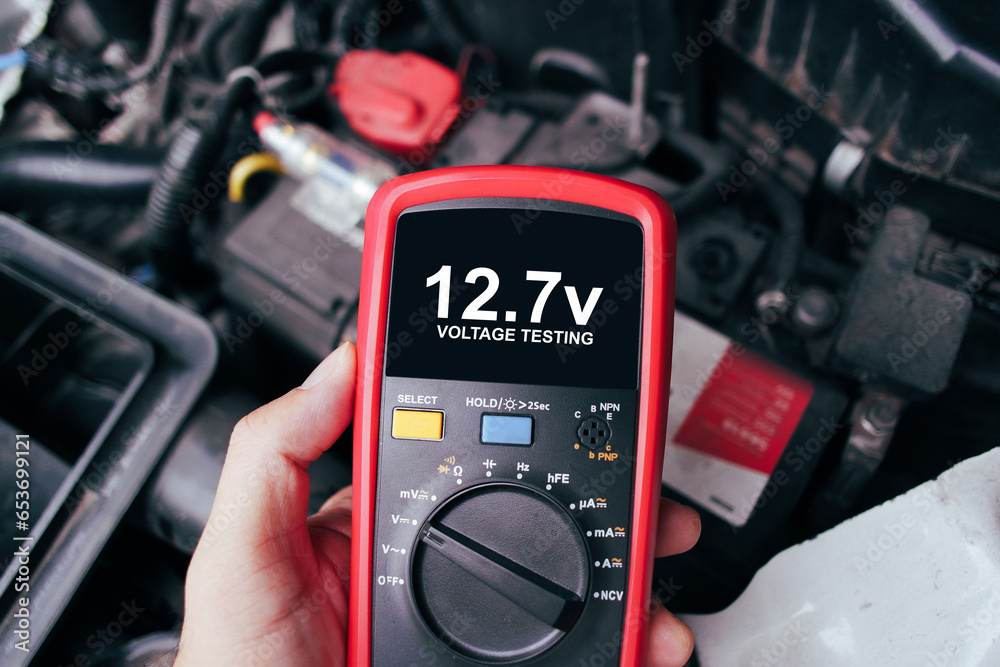 Car battery voltage testing with a digital multimeter by auto technician, Car voltage current display on black screen of digital multimeter, Car maintenance service concept - obrazy, fototapety, plakaty 