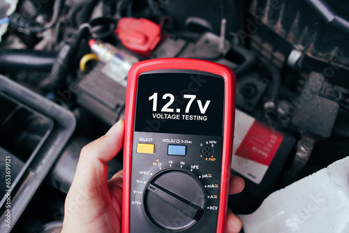 Car battery voltage testing with a digital multimeter by auto technician, Car voltage current display on black screen of digital multimeter, Car maintenance service concept