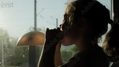 Close up view of child eats burger, sitting in a train compartment while traveling. Letters let yourself dream photo