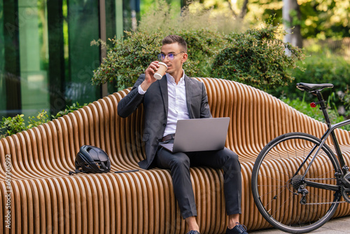 Handsome young businessman working on laptop and drinking coffee photo