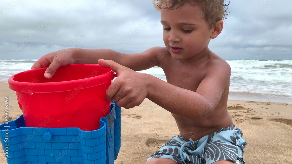 Cute infant boy playing at beach with buckets and water Cute infant boy playing at beach with buckets and water