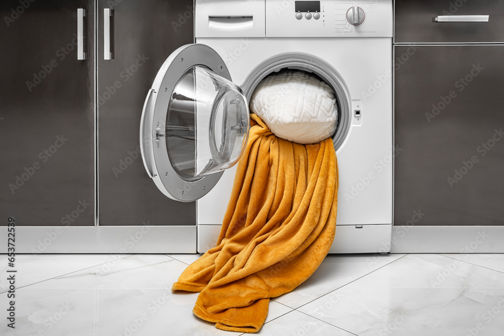 Washing large blankets and pillows in the washing machine. Stock Photo Adobe Stock