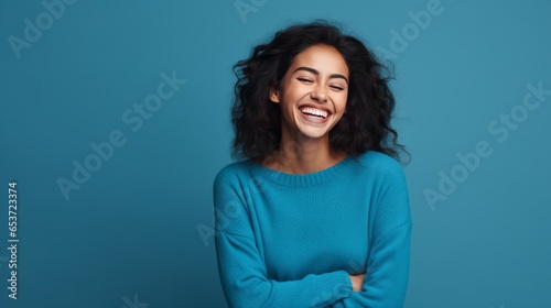 Hispanic woman standing over blue background smiling in love doing heart symbol shape with hands. romantic concept.