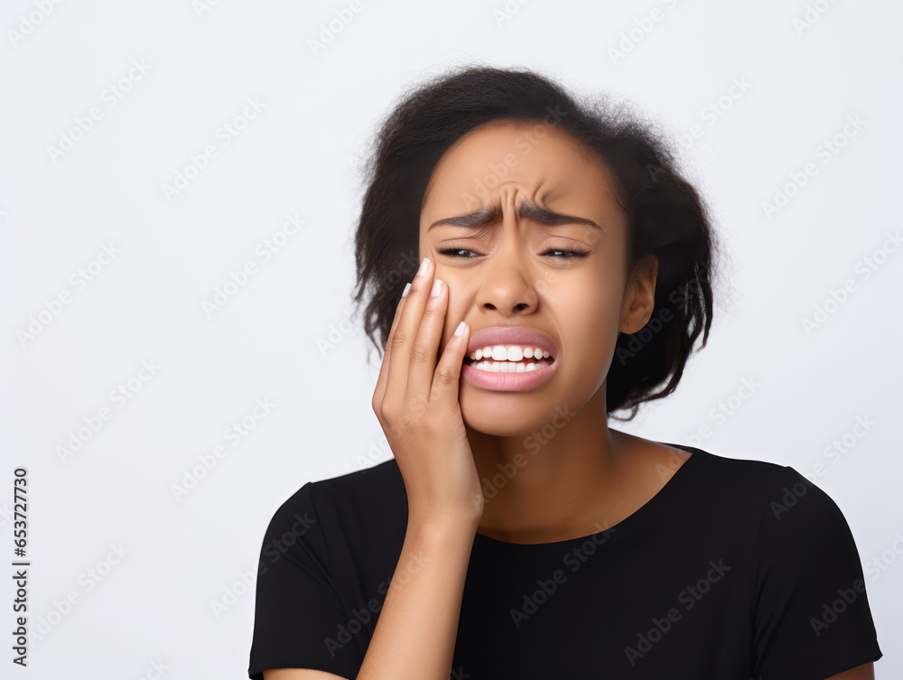 Young African American woman holding her cheek because she has a toothache Young African American woman holding her cheek because she has a toothache