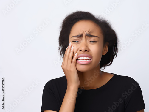 Young African American woman holding her cheek because she has a toothache