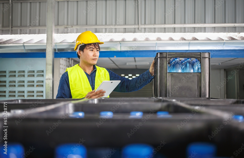 In a drink water factory, a tablet computer is being used by a skilled engineer or quality inspector to effectively monitor the process of checking bottled drinking water.