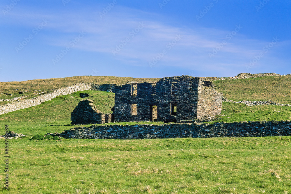 Old farm ruin on a meadow with stone walls in Shetland