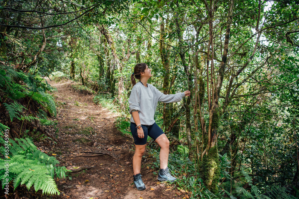 A young hiker rests by the trail smiling in nature A young hiker rests by the trail smiling in nature